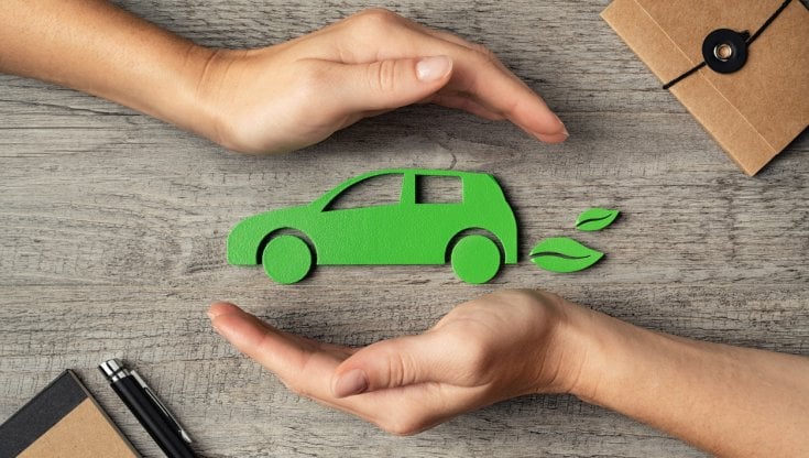 Due mani che accerchiano l'icona di un veicolo verde ed eco sostenibile